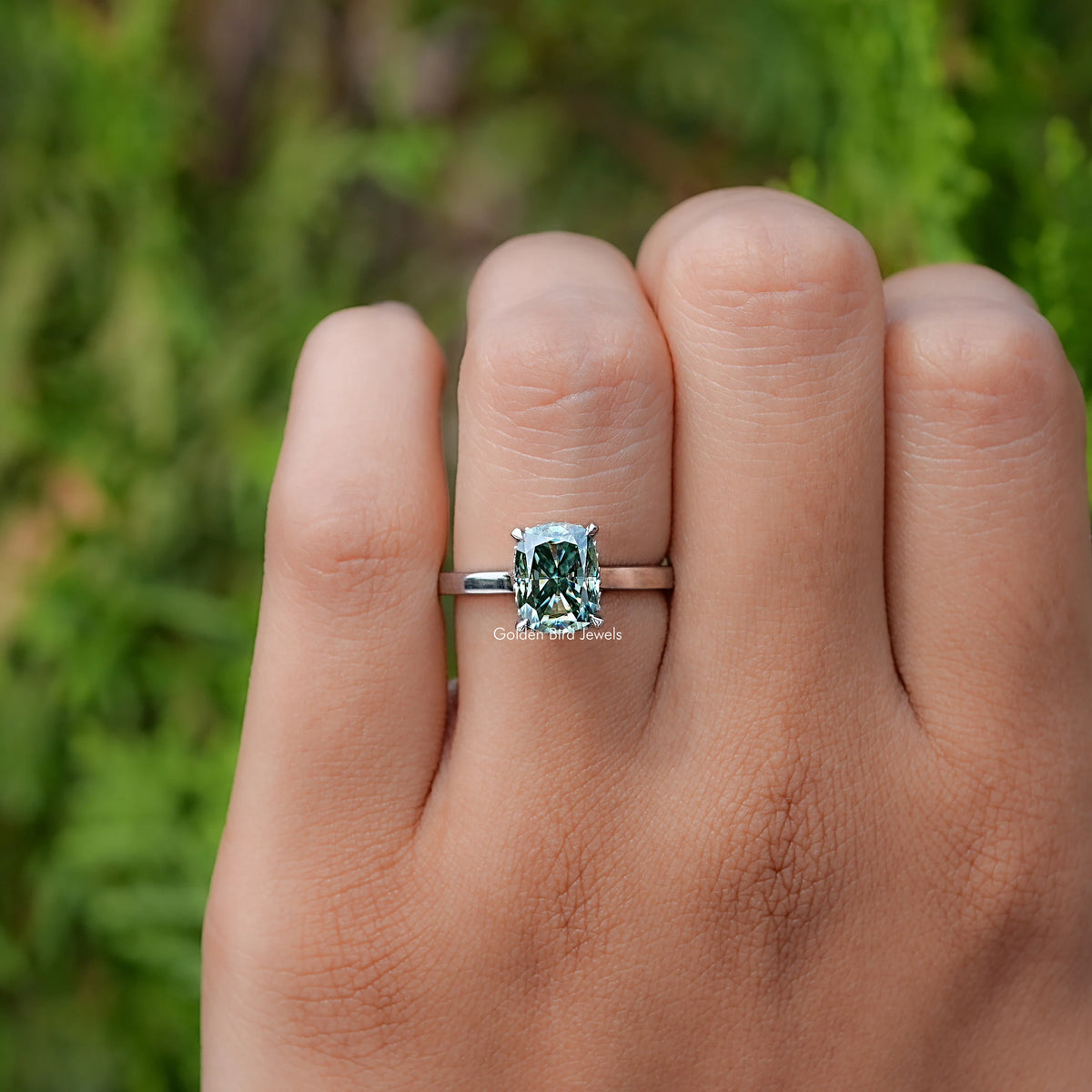 In finger front view of Fancy Green Elongated cushion moissanite hidden halo ring 