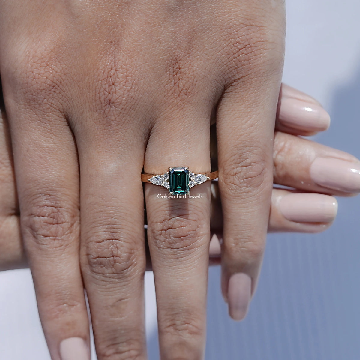 In front finger View Of Green Emerald cut engagement ring 