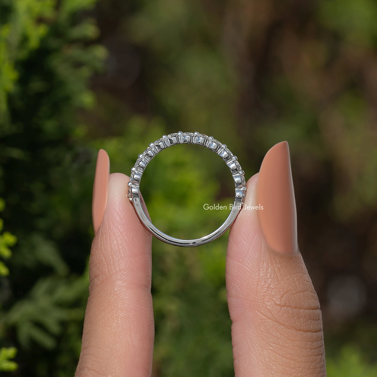 Silver-tone half eternity moissanite band with round stones, arched view on hand