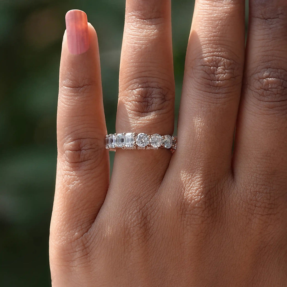 Slim round-cut moissanite band ring on finger, angled view