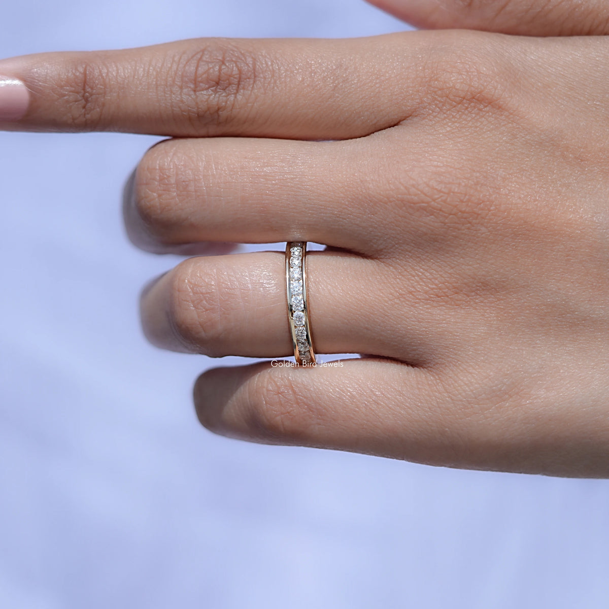 Silver half-eternity ring with channel-set stones, shown side profile on hand