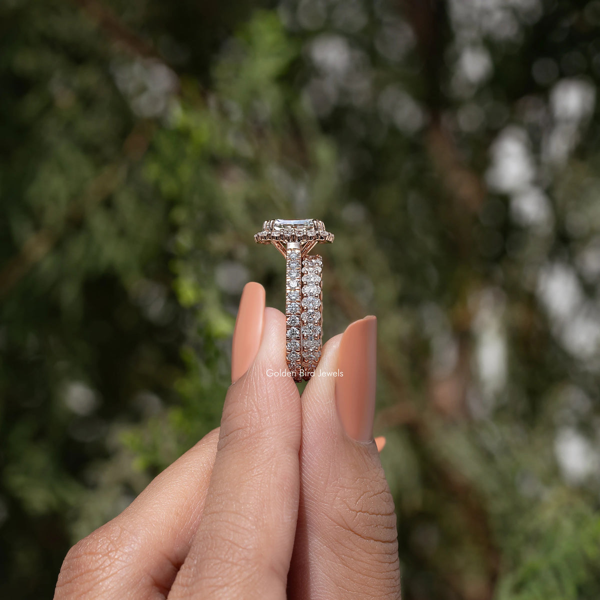 Radiant cut lab diamond halo bridal ring set held between fingers