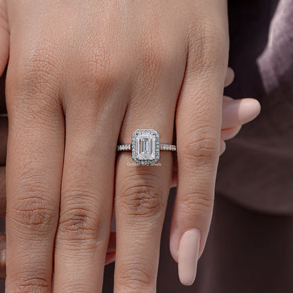 Sterling silver moissanite solitaire ring featuring an emerald-cut center stone on finger.