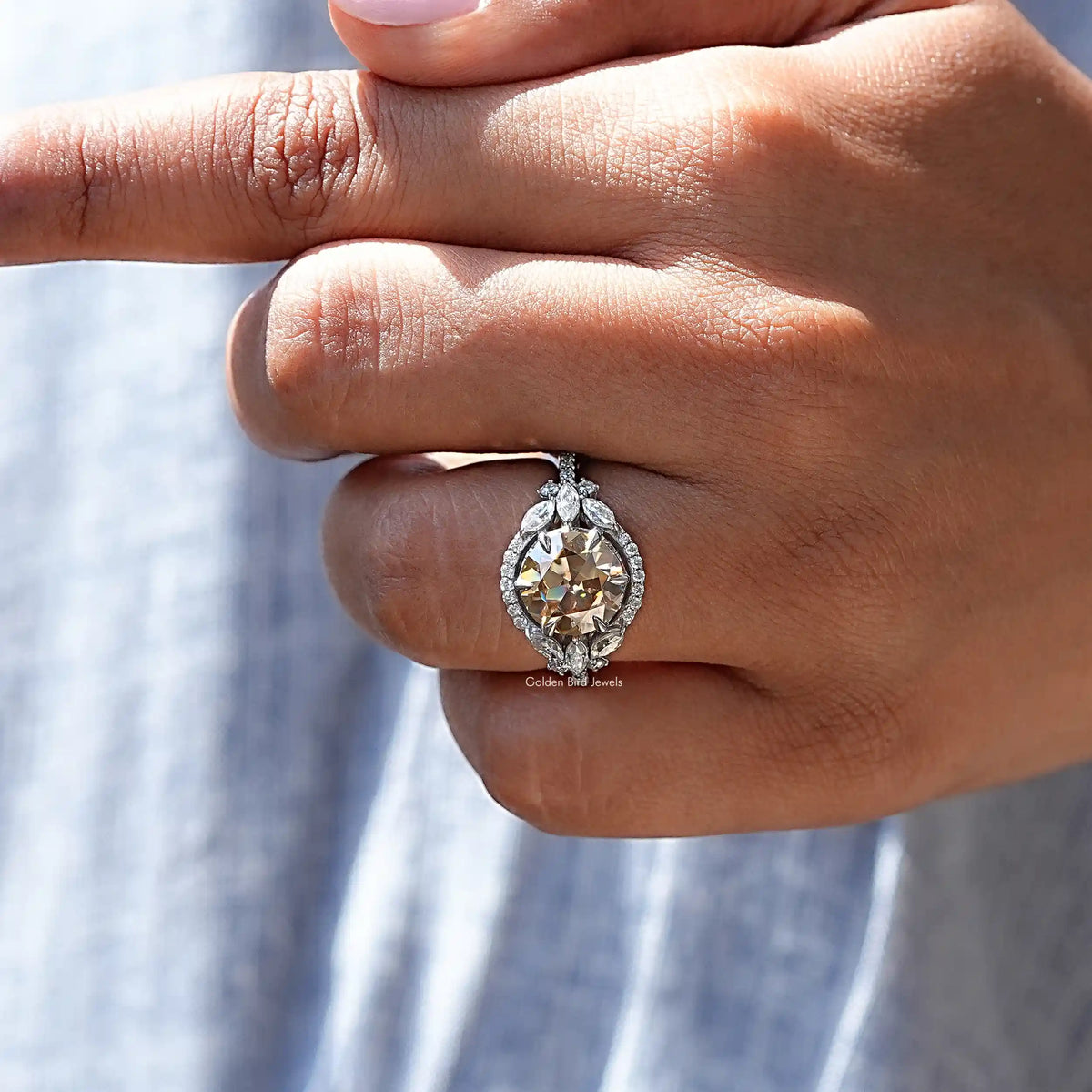 Silver halo cluster ring with round champagne center stone, hands holding