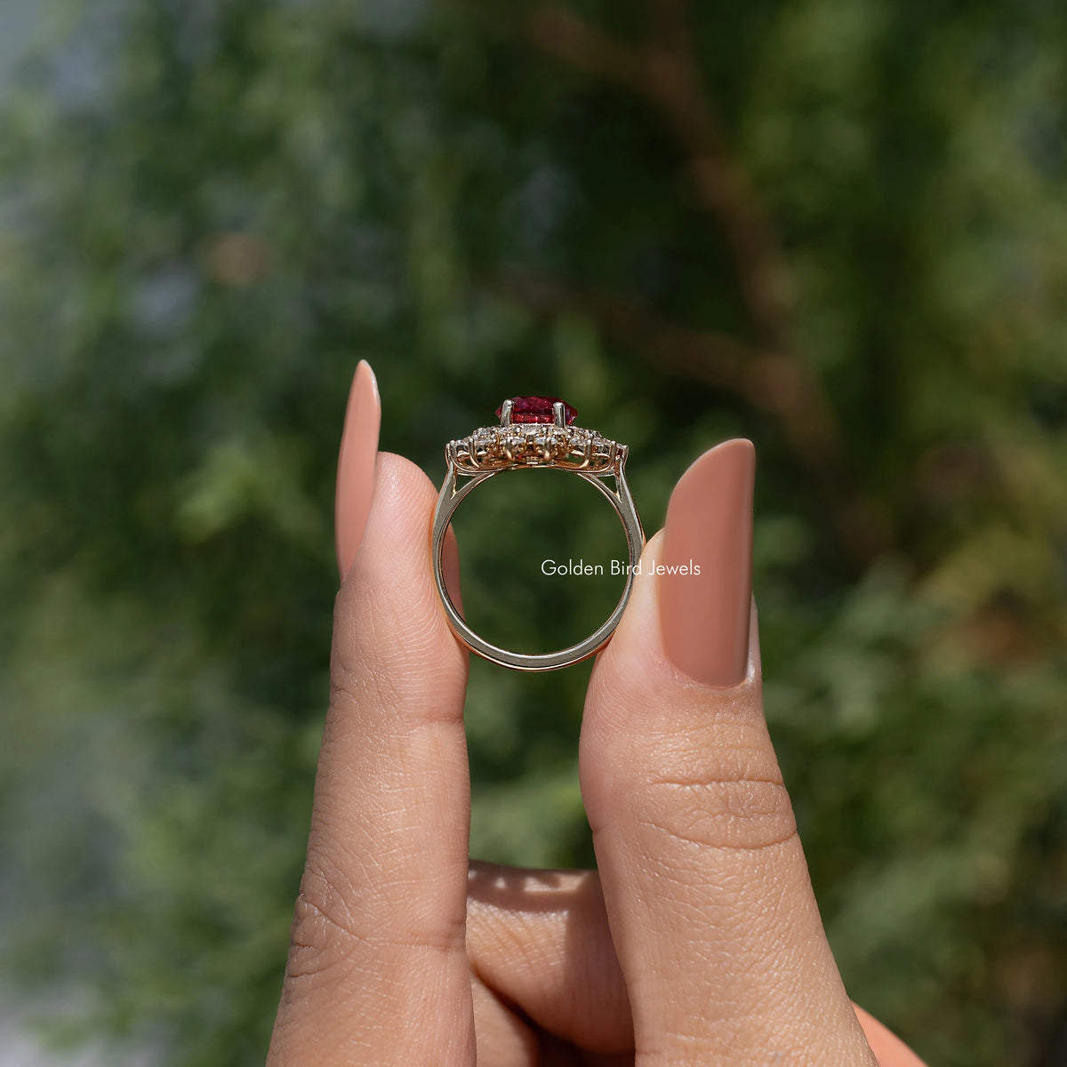 Halo engagement ring with oval centerpiece and small round stones, worn on fingertip