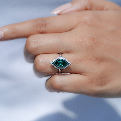 Teal marquise halo engagement ring with rectangular center stone, ring on resting hand