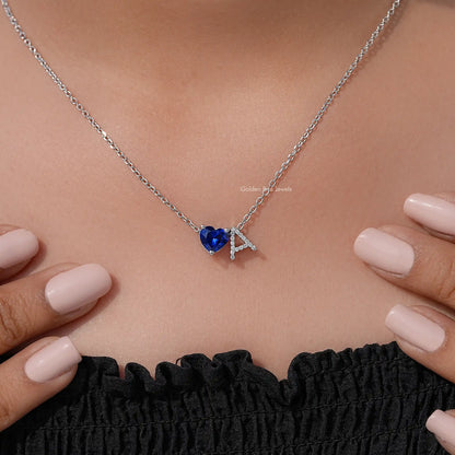Blue heart pendant with letter A charm on a silver chain, styled on neckline