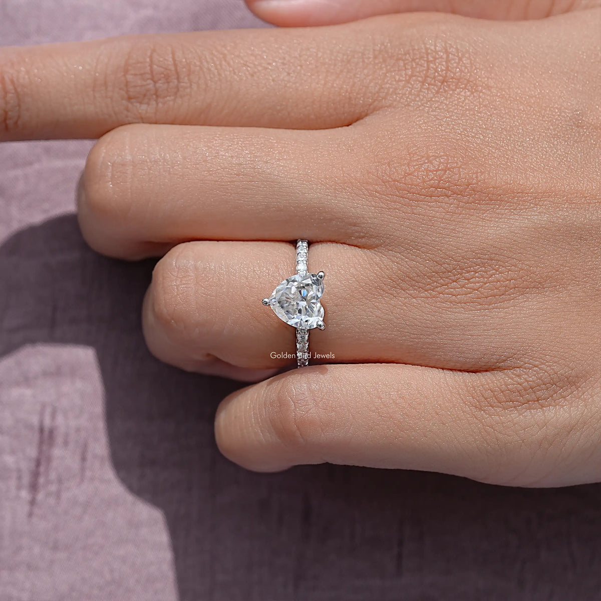 Heart-shaped moissanite solitaire ring, silver band, side view on fingers