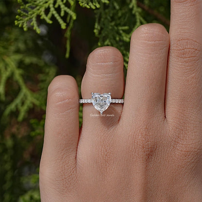 Heart-shaped moissanite solitaire ring with thin silver band on hand