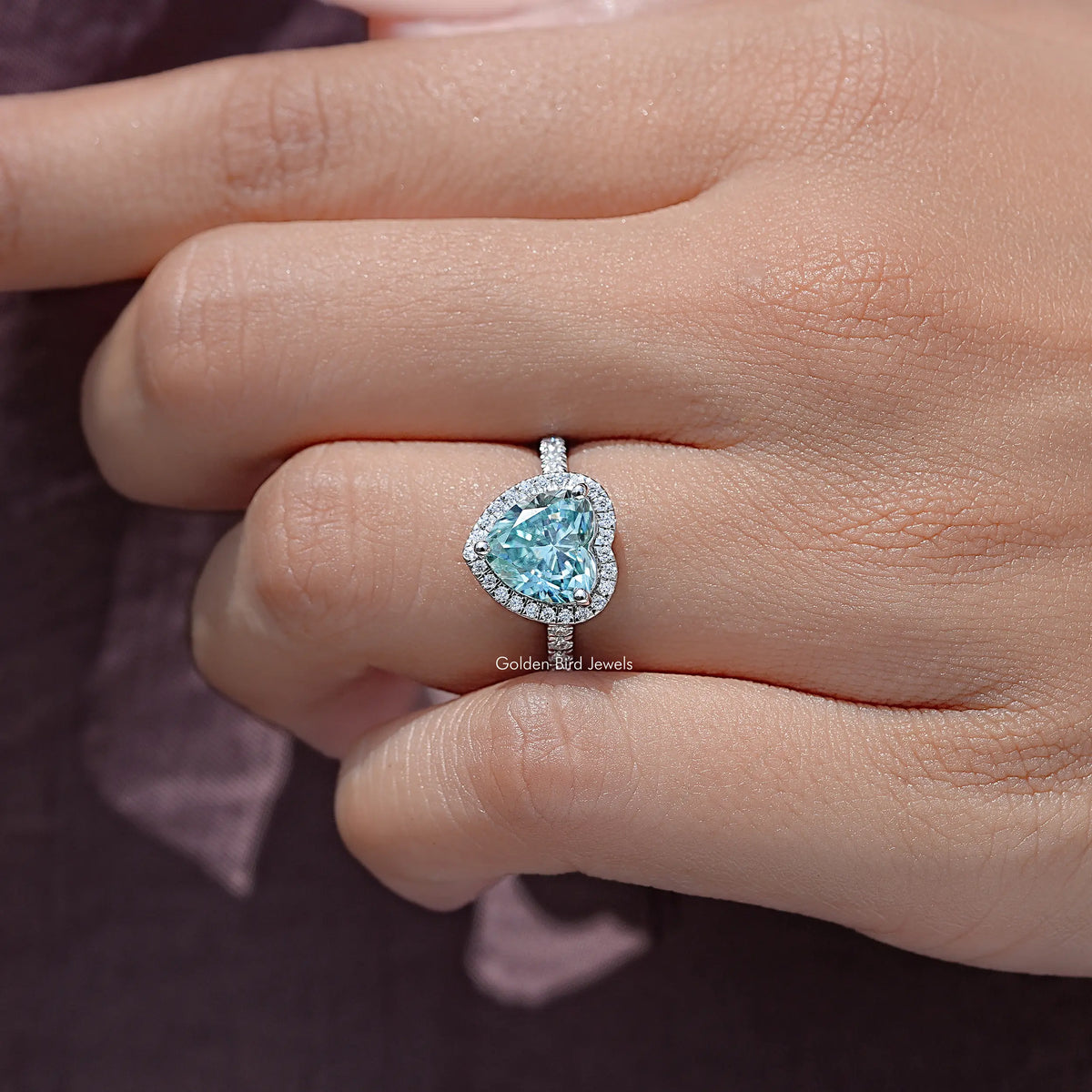Heart-cut blue accent wedding ring with halo on hand