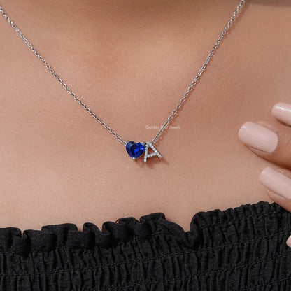Blue heart sapphire-like pendant with letter A charm, silver chain close-up