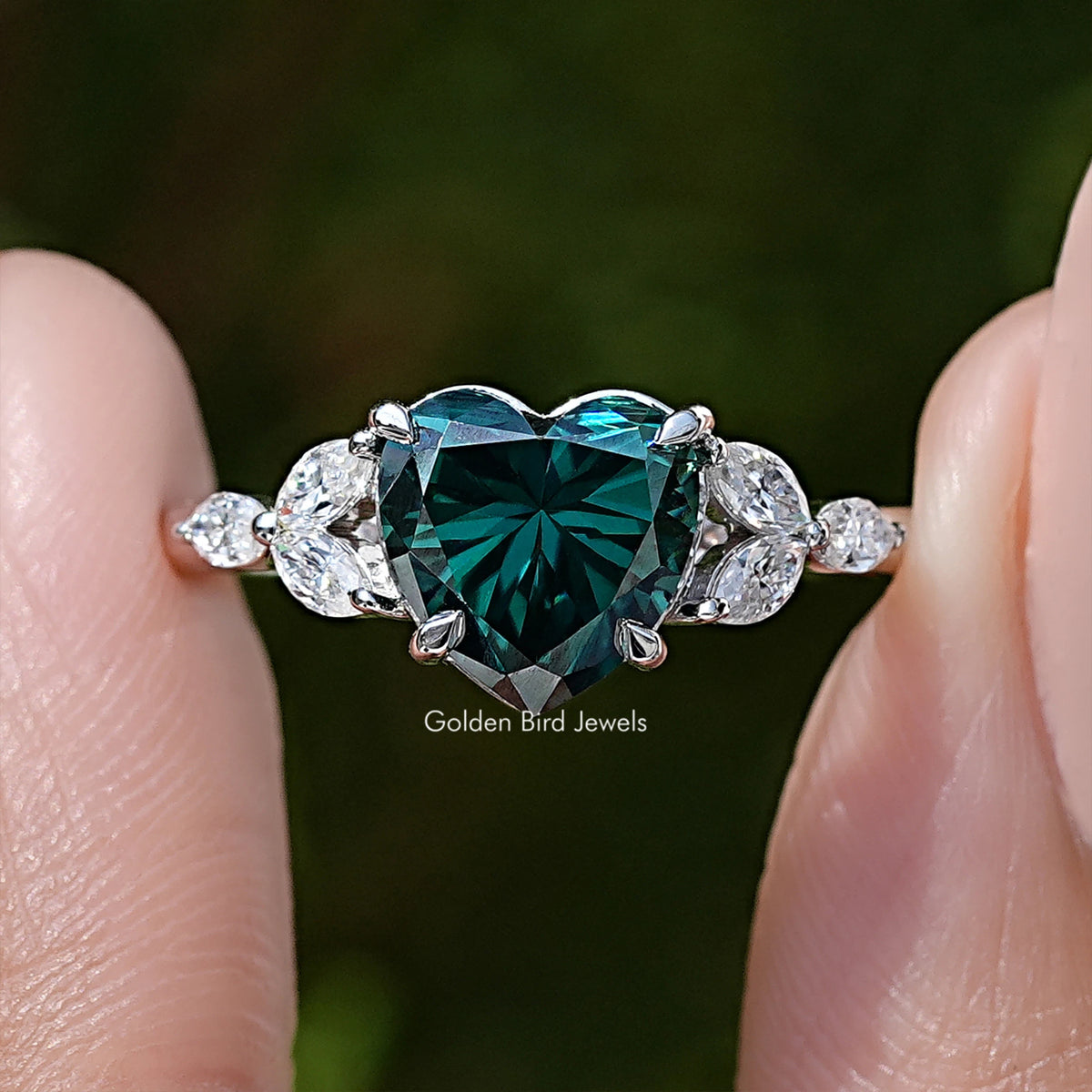Close-up: green moissanite center with halo and round side stones on sterling silver