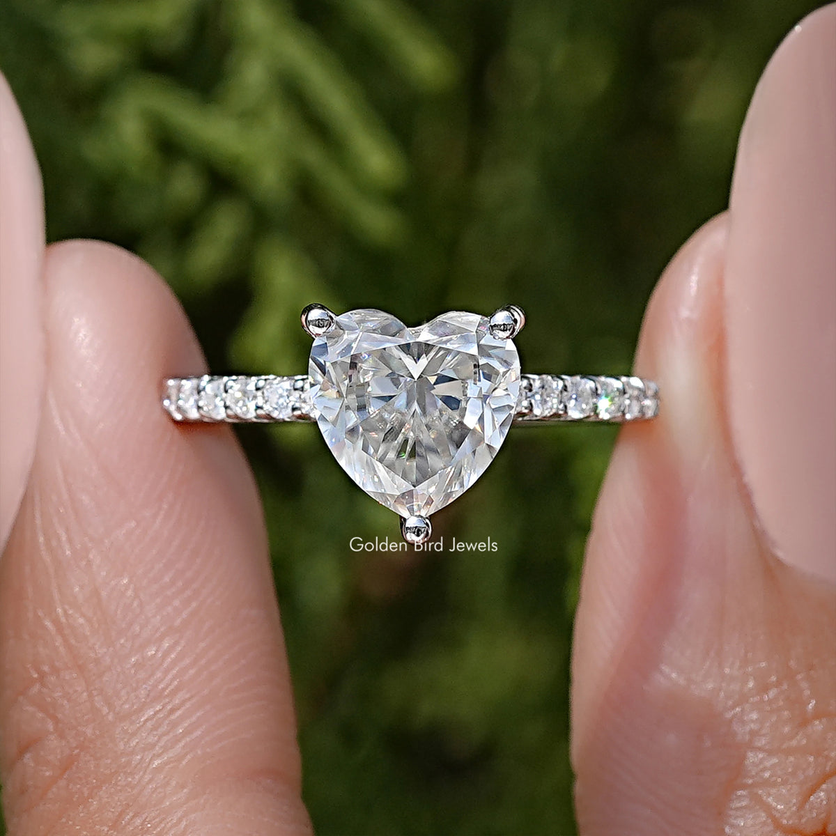 Close-up of heart-shaped moissanite solitaire ring with silver prongs