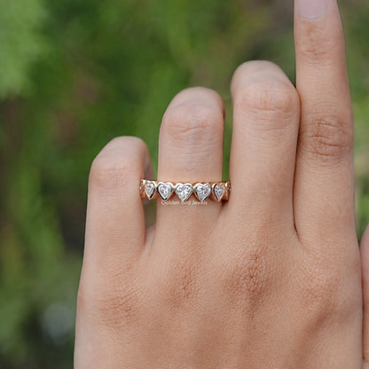Heart-shaped eternity band ring with bezel-set stones, worn on a finger
