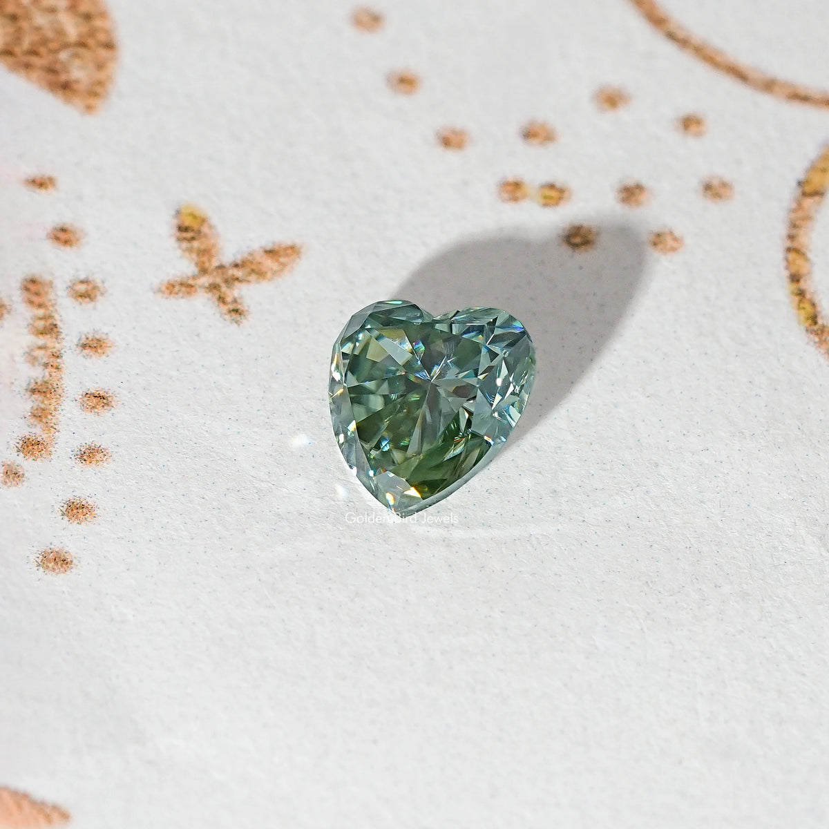 Heart-cut moissanite gemstone, light green-blue with faceted crown and shine.