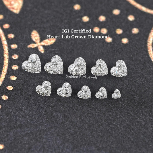 Assorted loose heart-shaped lab diamonds in two rows, faceted sparkle