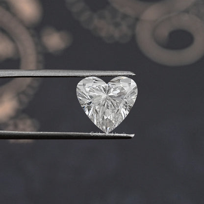 Heart lab diamond held in metal tweezers, large brilliant facets close-up