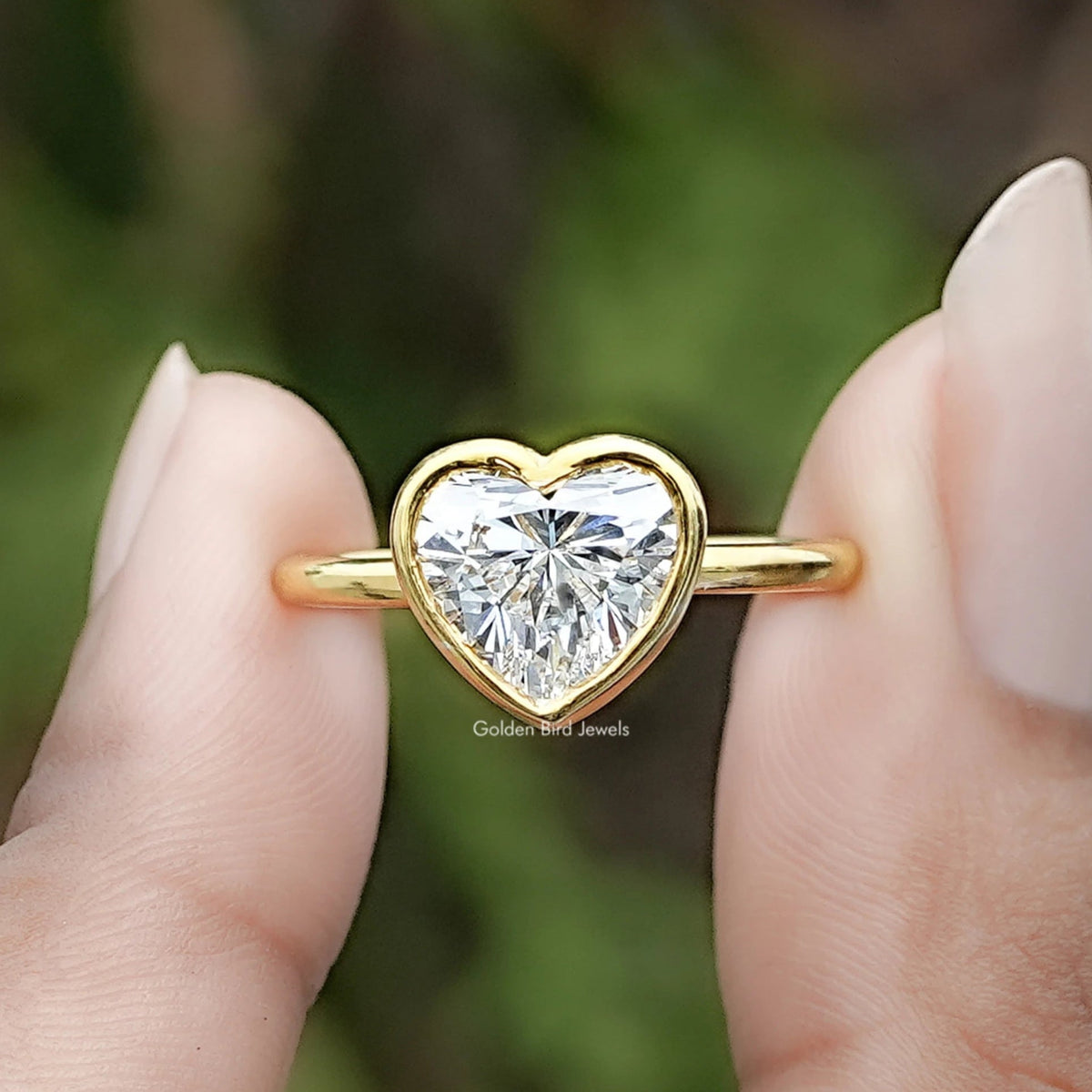 Heart Shaped Lab Diamond Bezel Set Ring Between Two Fingers