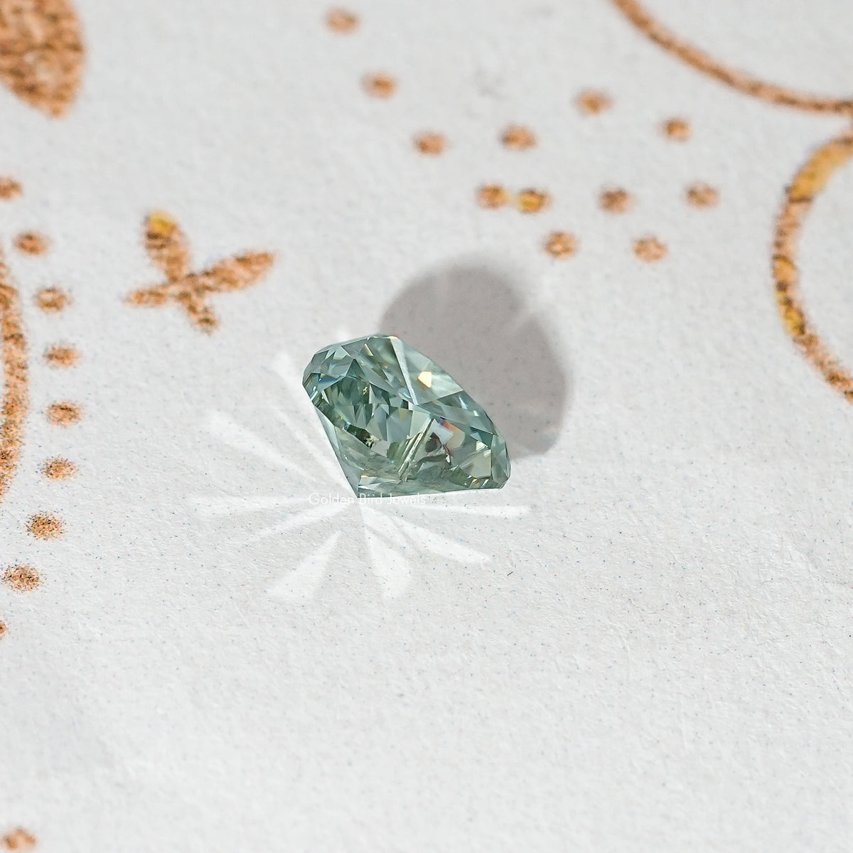 Heart-cut moissanite gemstone, green-blue with multi-facet pattern and sparkle.