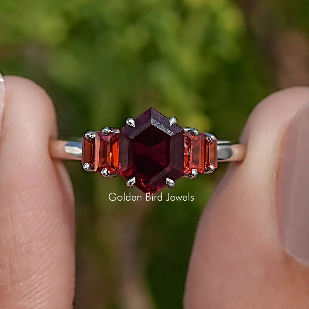 Front close-up of five red hexagon-cut gemstones set in silver-tone ring