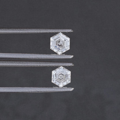 Faceted hexagon-cut moissanite pair held between metal tweezers