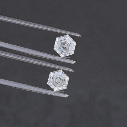 Faceted hexagon-cut moissanite pair held between metal tweezers