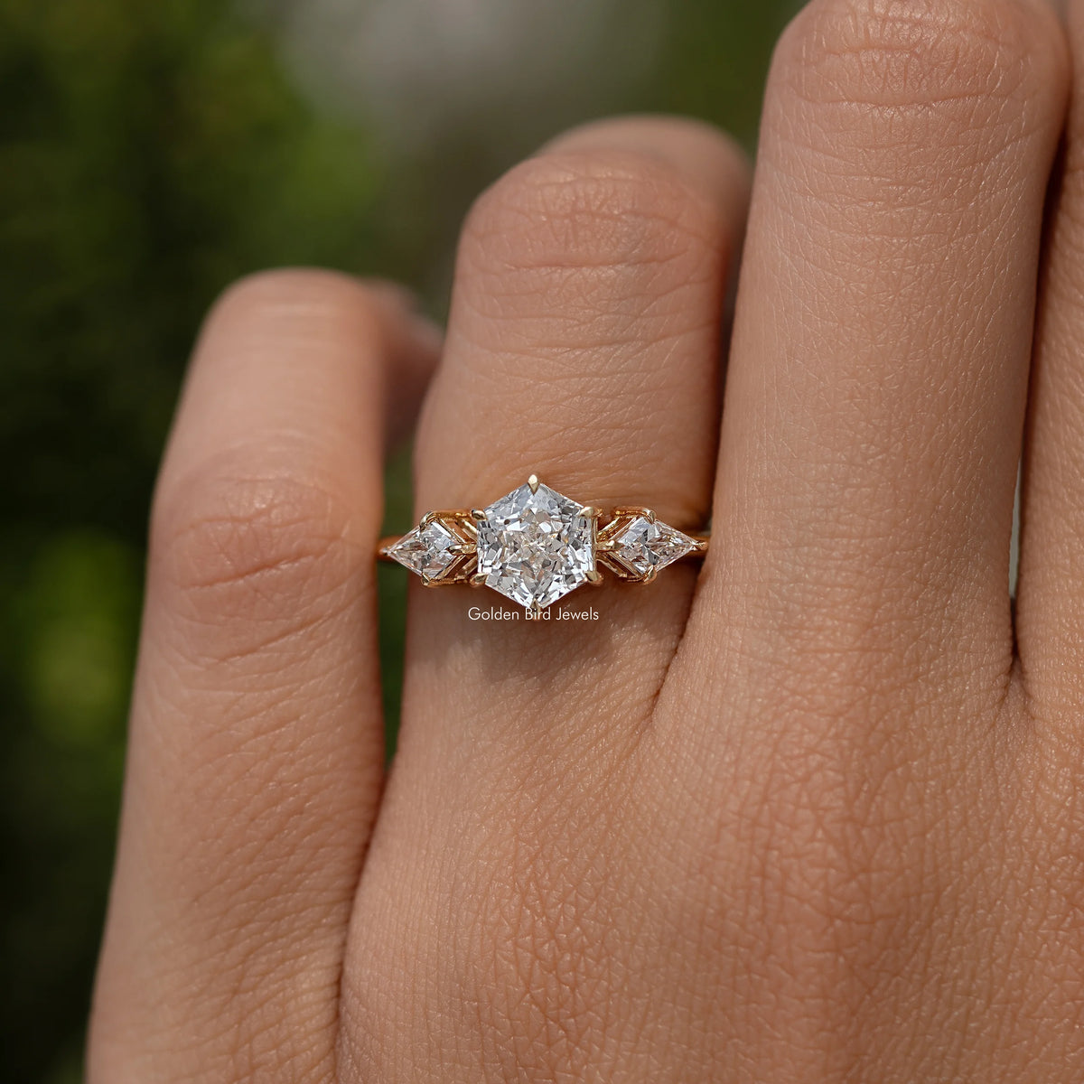 Three-stone diamond ring with radiant center stone and two side stones, yellow gold setting