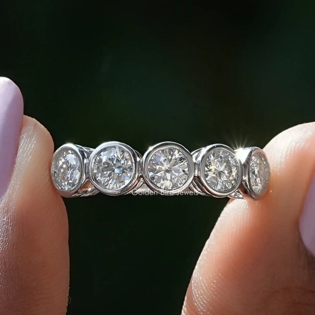 Silver five-stone round moissanite band with bezel-set stones, close-up side view