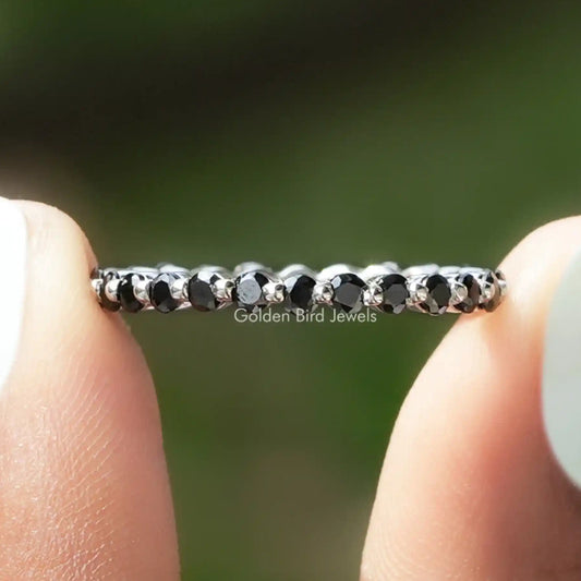 Full eternity band with dark round bezel-set gemstones along the silver-tone ring