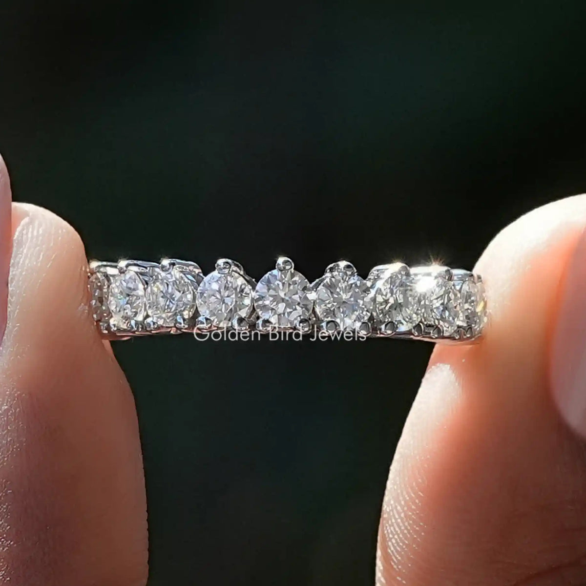 Moissanite wedding band with multiple round clear stones across the band