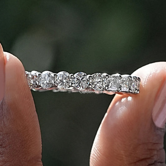 Silver moissanite eternity band with round and princess-cut stones, close-up on hands