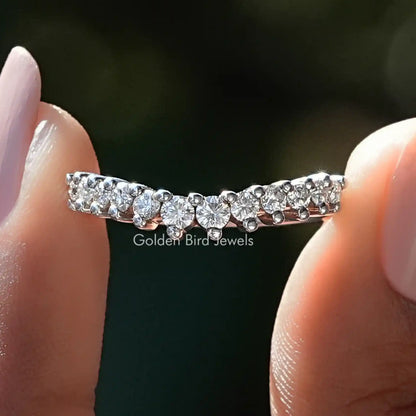 Curved round-cut moissanite wedding band with multiple clear stones, silver-tone setting