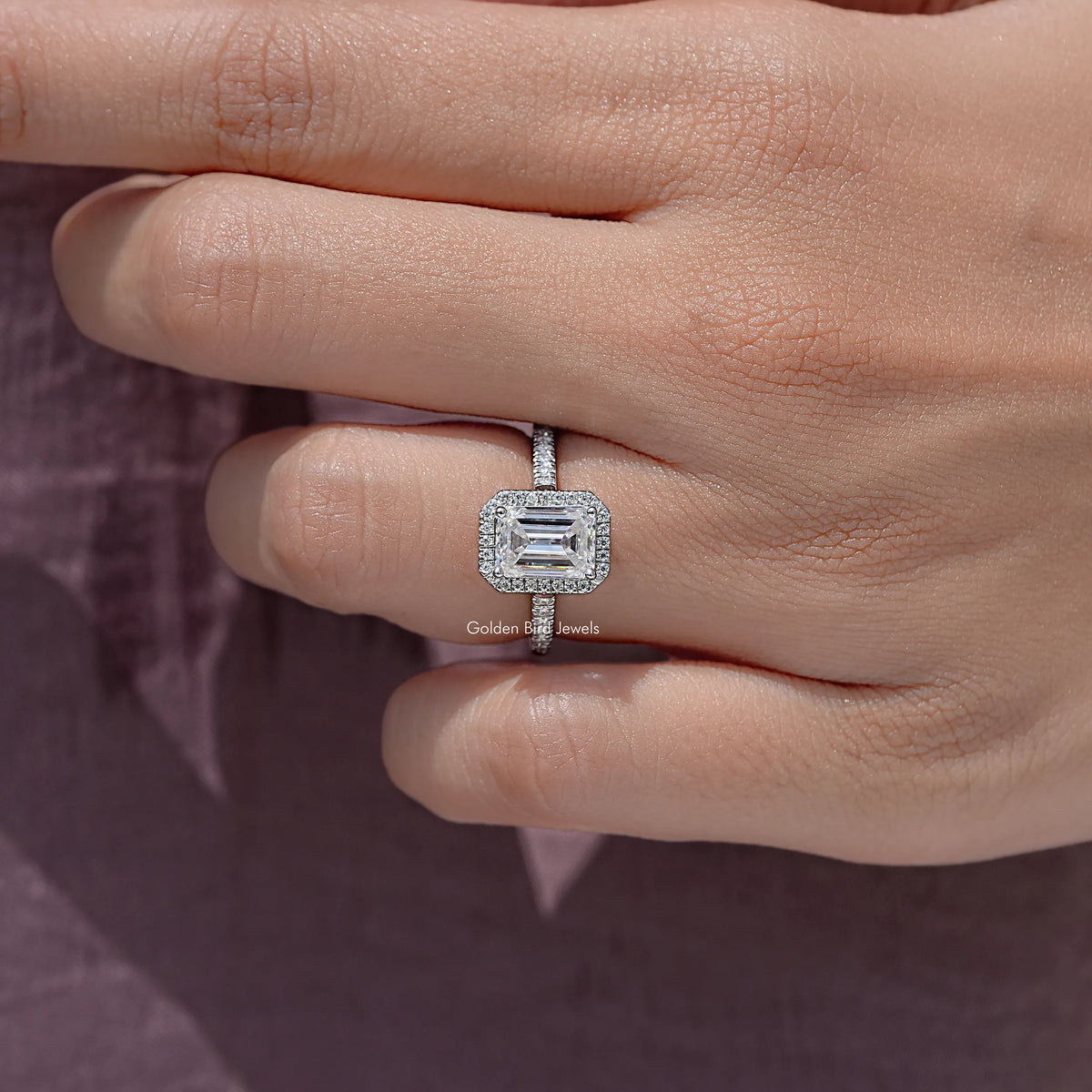 Sterling silver moissanite solitaire ring, emerald-cut center stone with pave detailing.