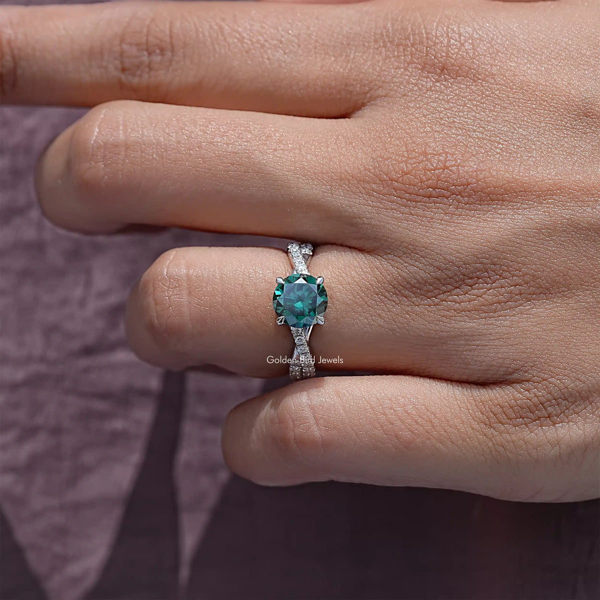 Green moissanite gemstone ring with twisted silver accent band on finger