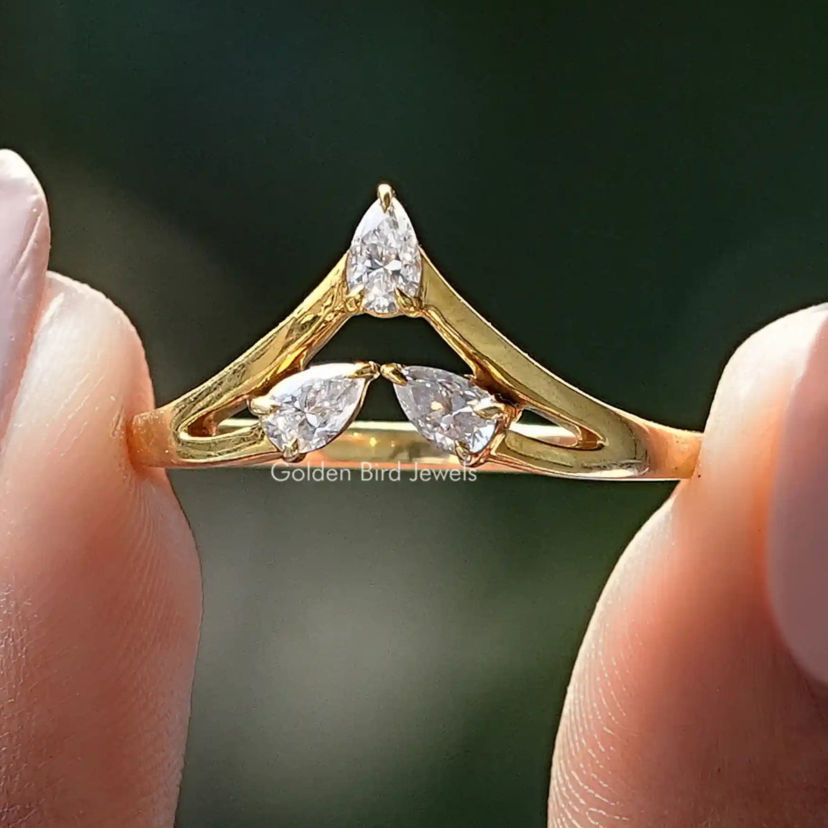 Curved gold wedding band with three pear-cut moissanite stones
