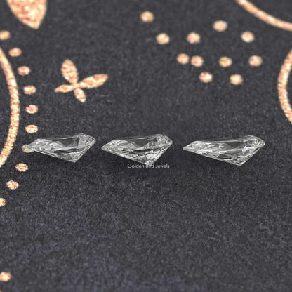 Loose pear-cut lab diamond, three stones displayed on dark fabric