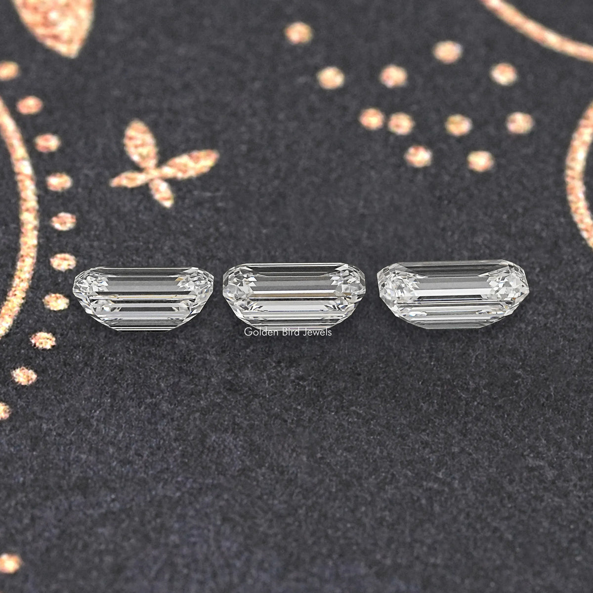 Three emerald-cut lab diamonds on dark velvet, clear step-cut stones.