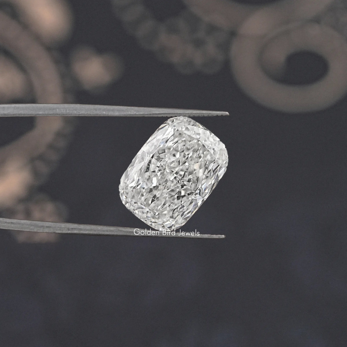 Loose elongated cushion-cut diamond, clear faceted stone held in tweezers
