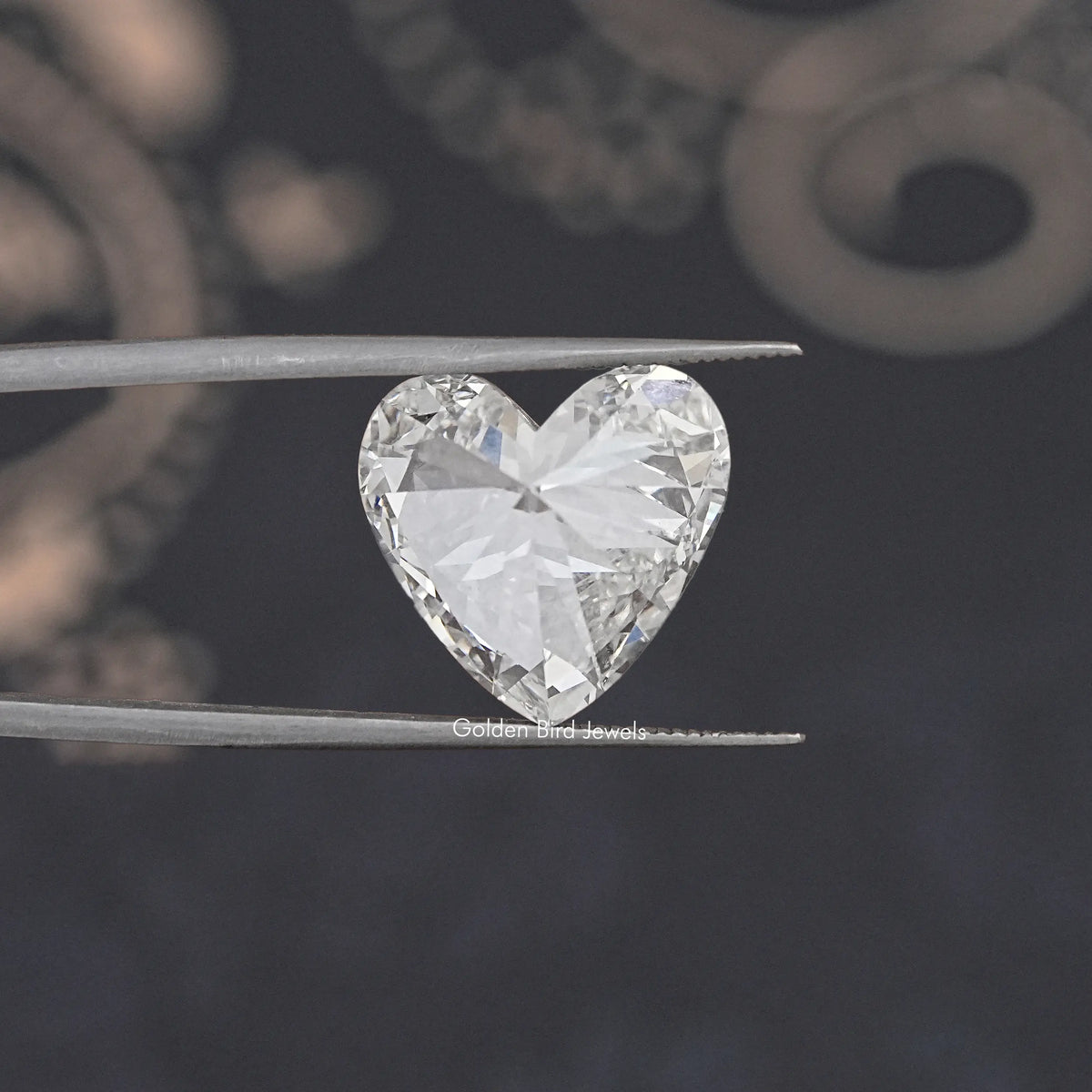 Heart cut lab-grown diamond held in tweezers, angled view