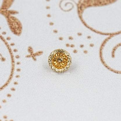Centered round golden-yellow moissanite gemstone with faceted surface