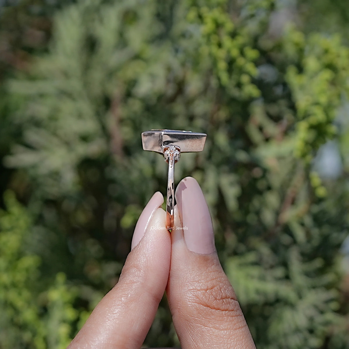Rose-gold bezel kite moissanite ring with central stone and small side prongs