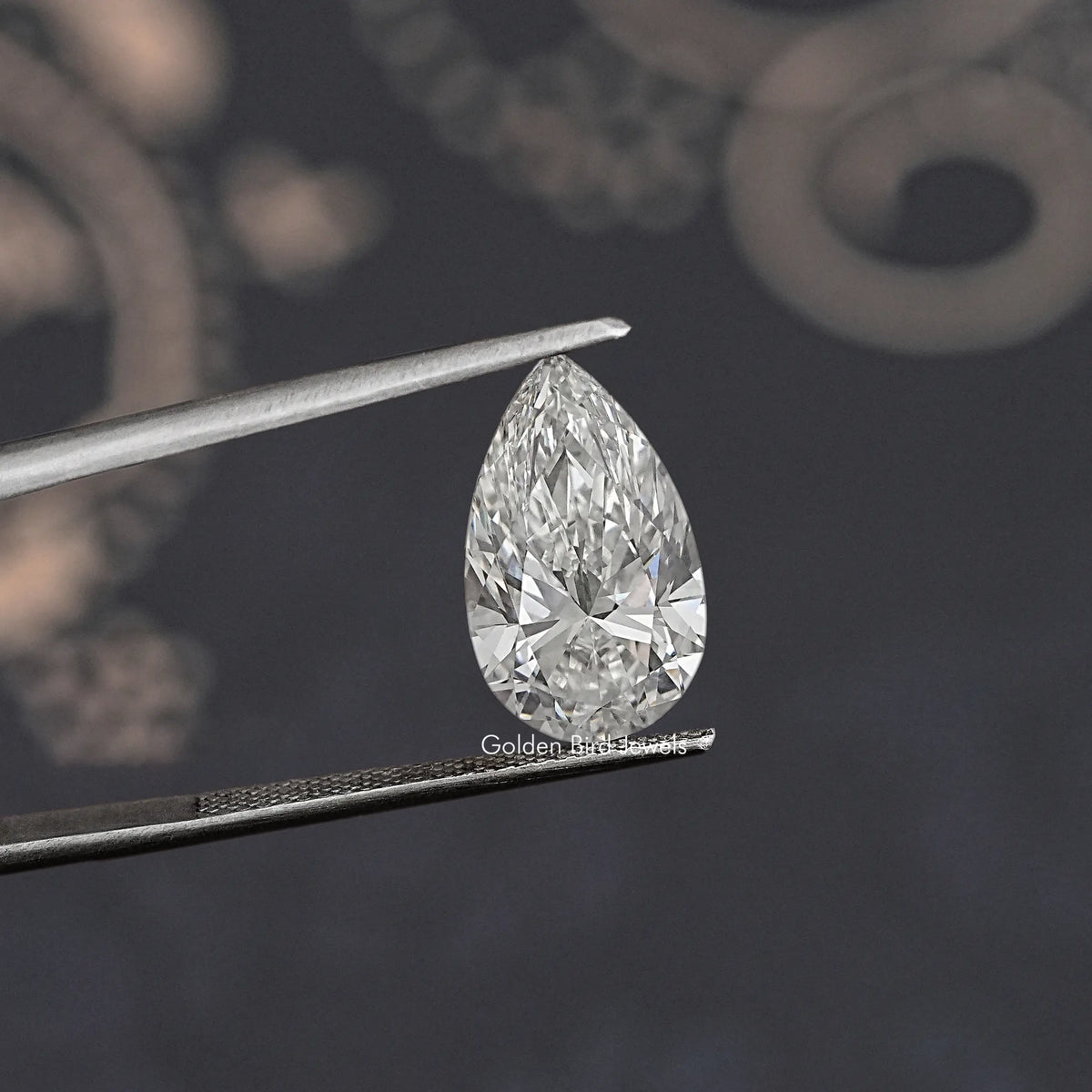 Loose pear-cut lab diamond angled between metal tweezers, clear white facets.