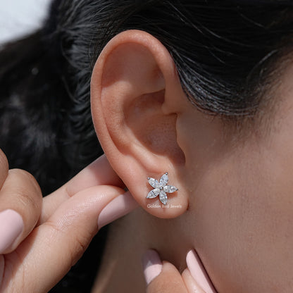 Marquise-cut diamond floral stud earrings in hand near earlobe