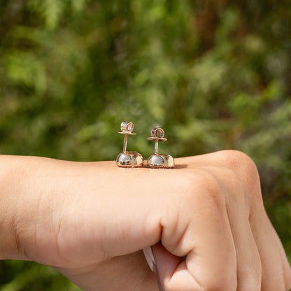 Cushion-cut diamond stud earrings with milgrain bezel in gold settings on palm