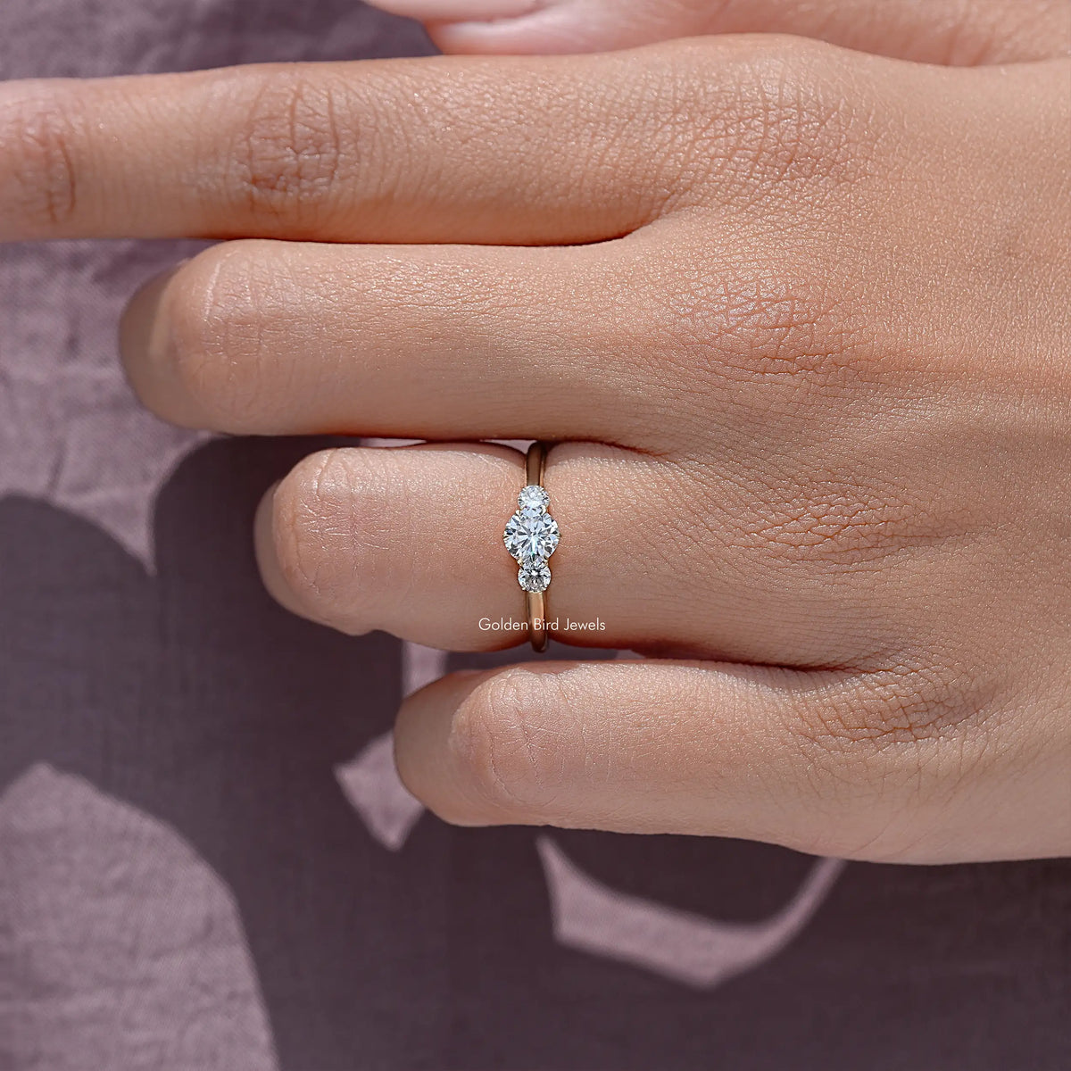 Three-stone round cut diamond ring with prong-set stones, close-up side view