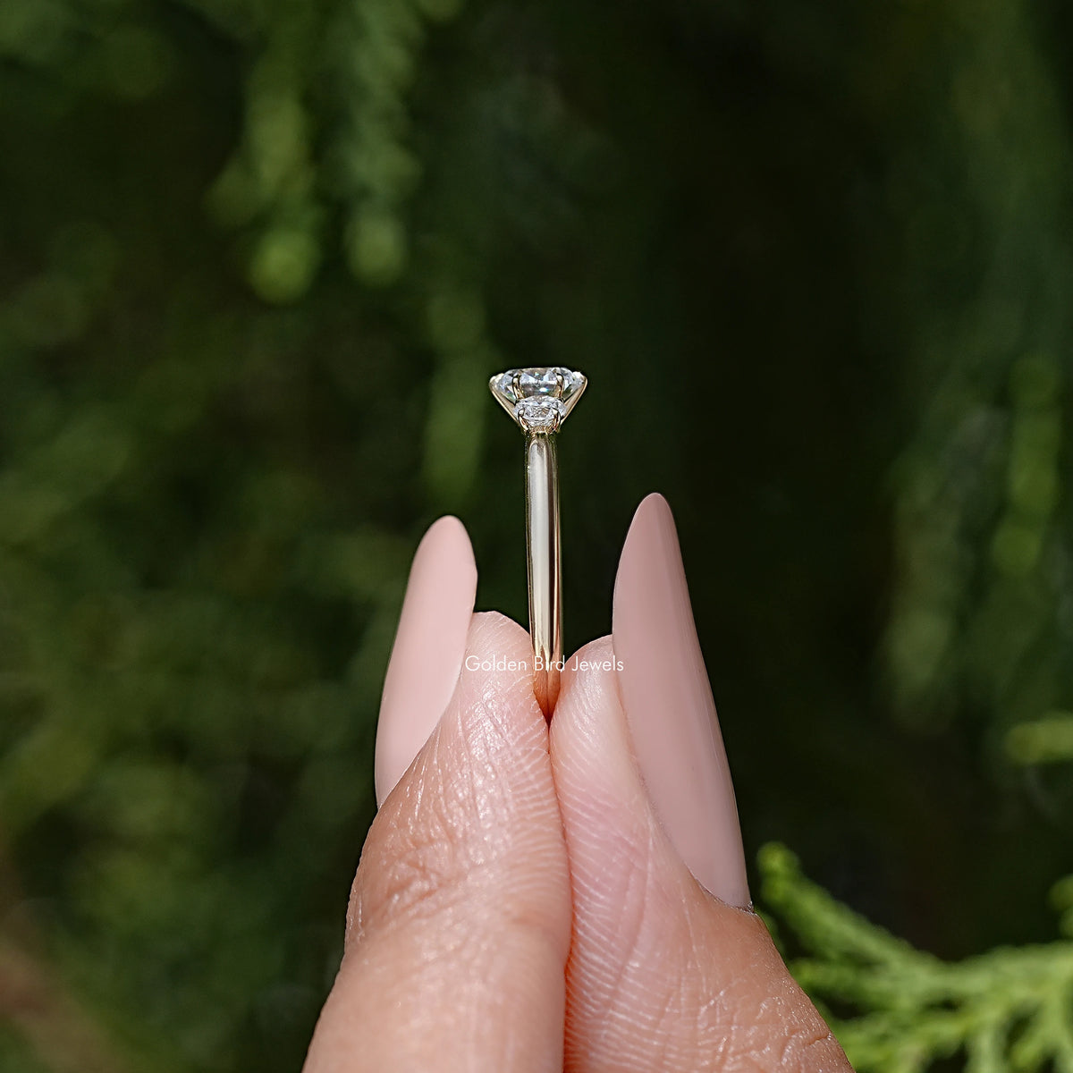 Three-stone round diamond engagement ring showing center stone in a six-prong setting