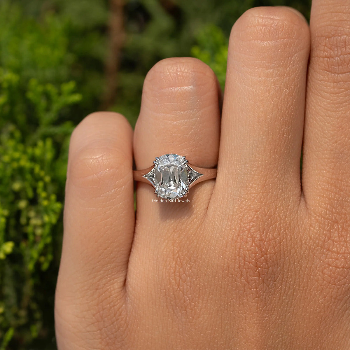 Cushion-cut diamond split-shank ring with halo, close-up on finger