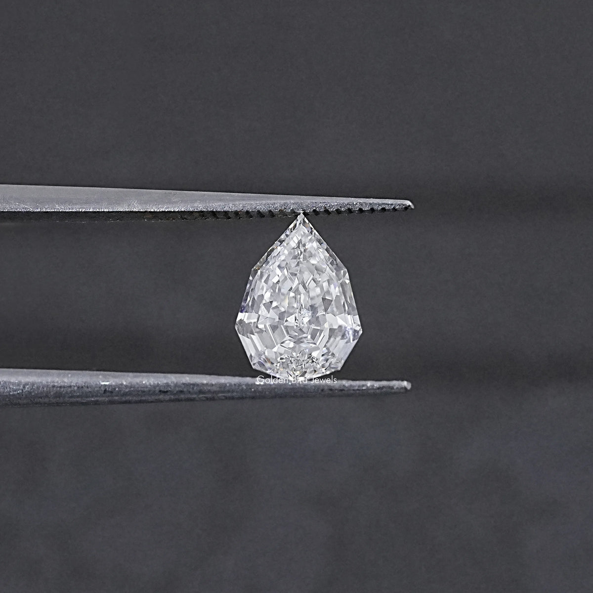 Lab-grown pear-cut diamond held between metal tweezer tips, step-cut facets