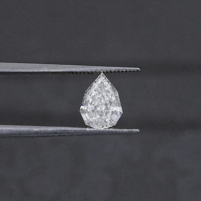 Lab-grown pear-cut diamond held between metal tweezer tips, step-cut facets