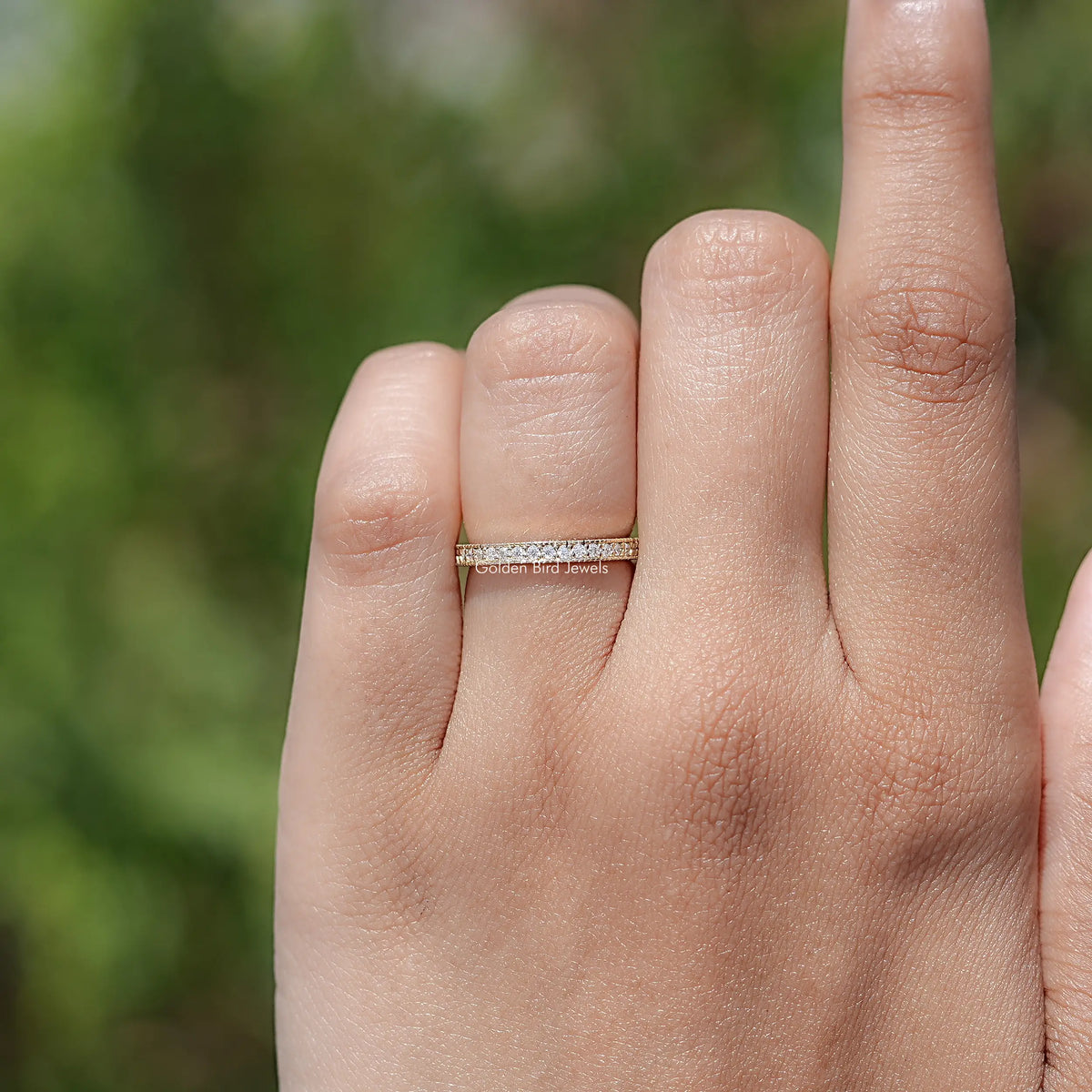 Gold-tone full eternity ring on hand, round-cut diamonds around the band